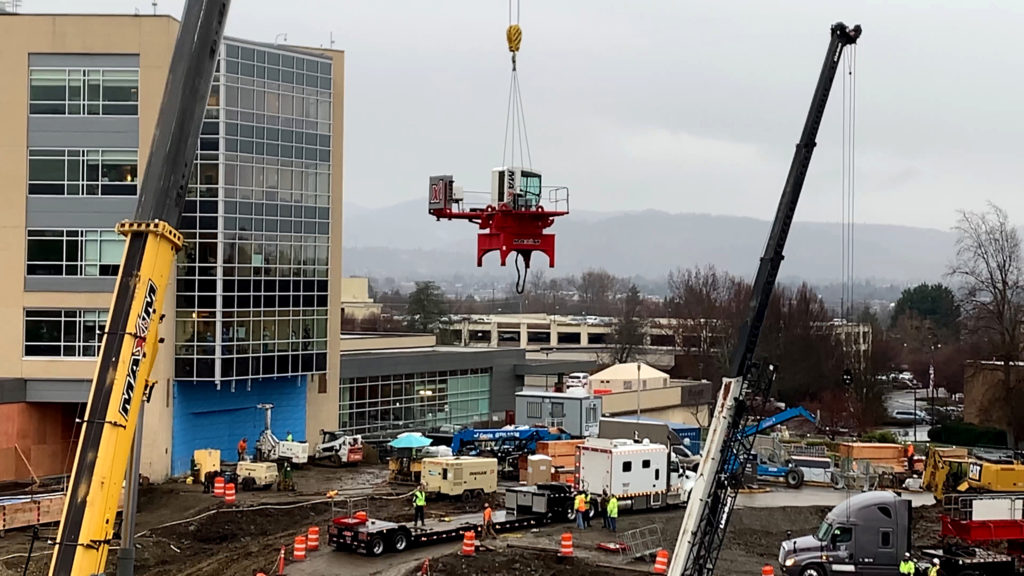 The crane's cab is lifted into the air by a smaller crane.