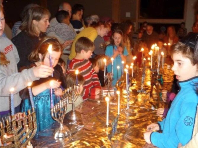 Sarah Aaronson lights a menorah at Temple Emek Shalom Hanukkah party.